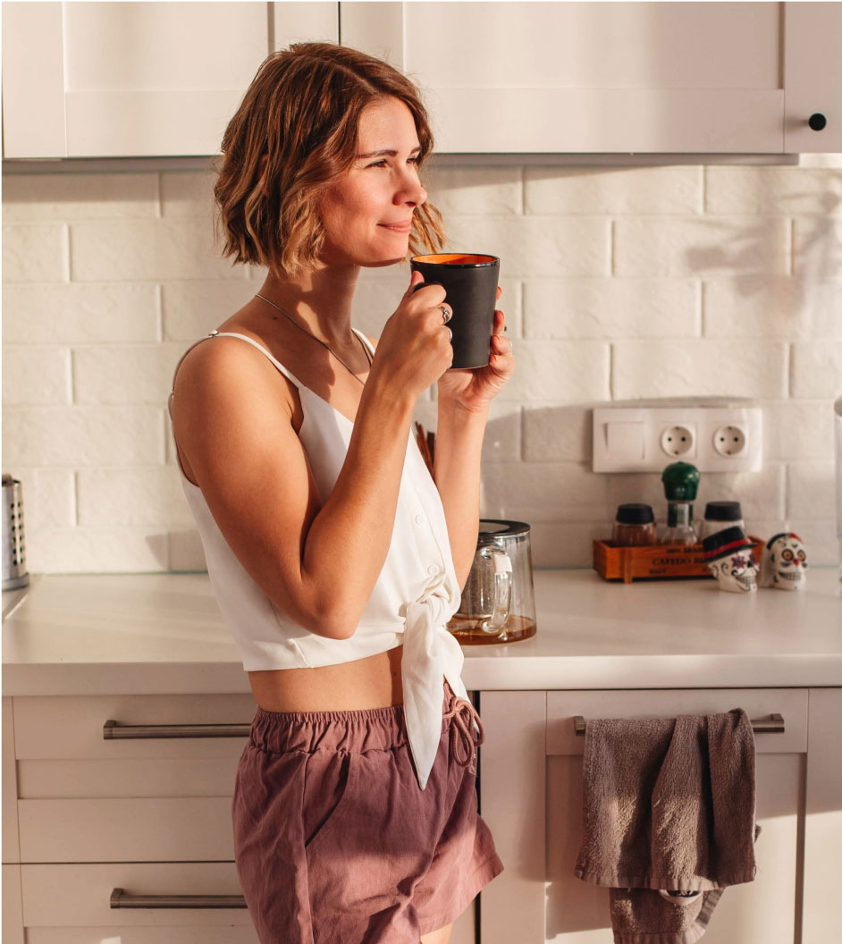 Woman Holding Cup Standing in the Kitchen